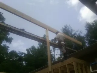 Carpenter setting a ridge beam over a new addition frame — Ice Dam Removal by Roofing Brothers in Borup
