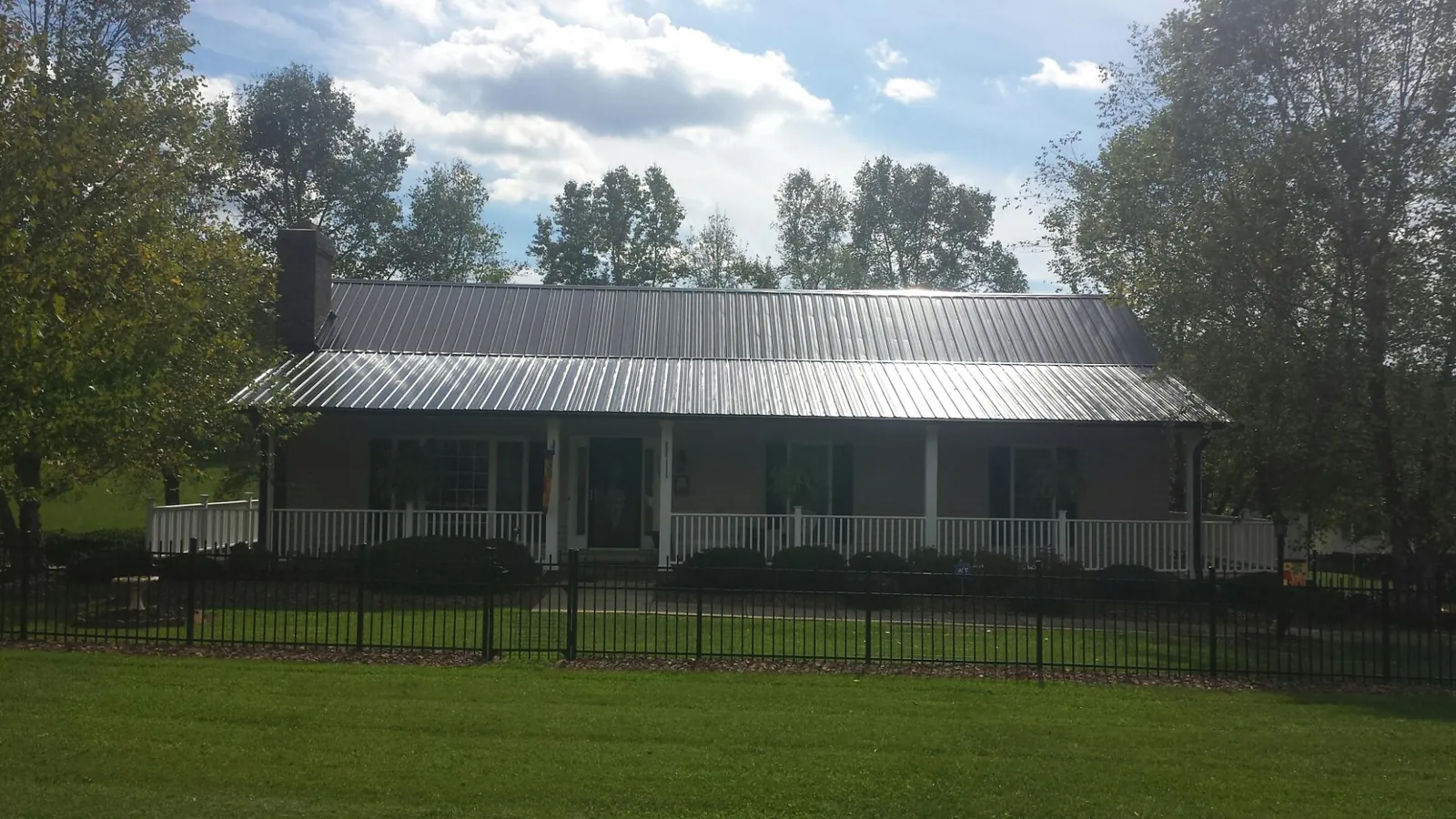 Gray metal roof on a brick ranch with a full width front porch — Gutter Guard Installation work by our crew in Borup