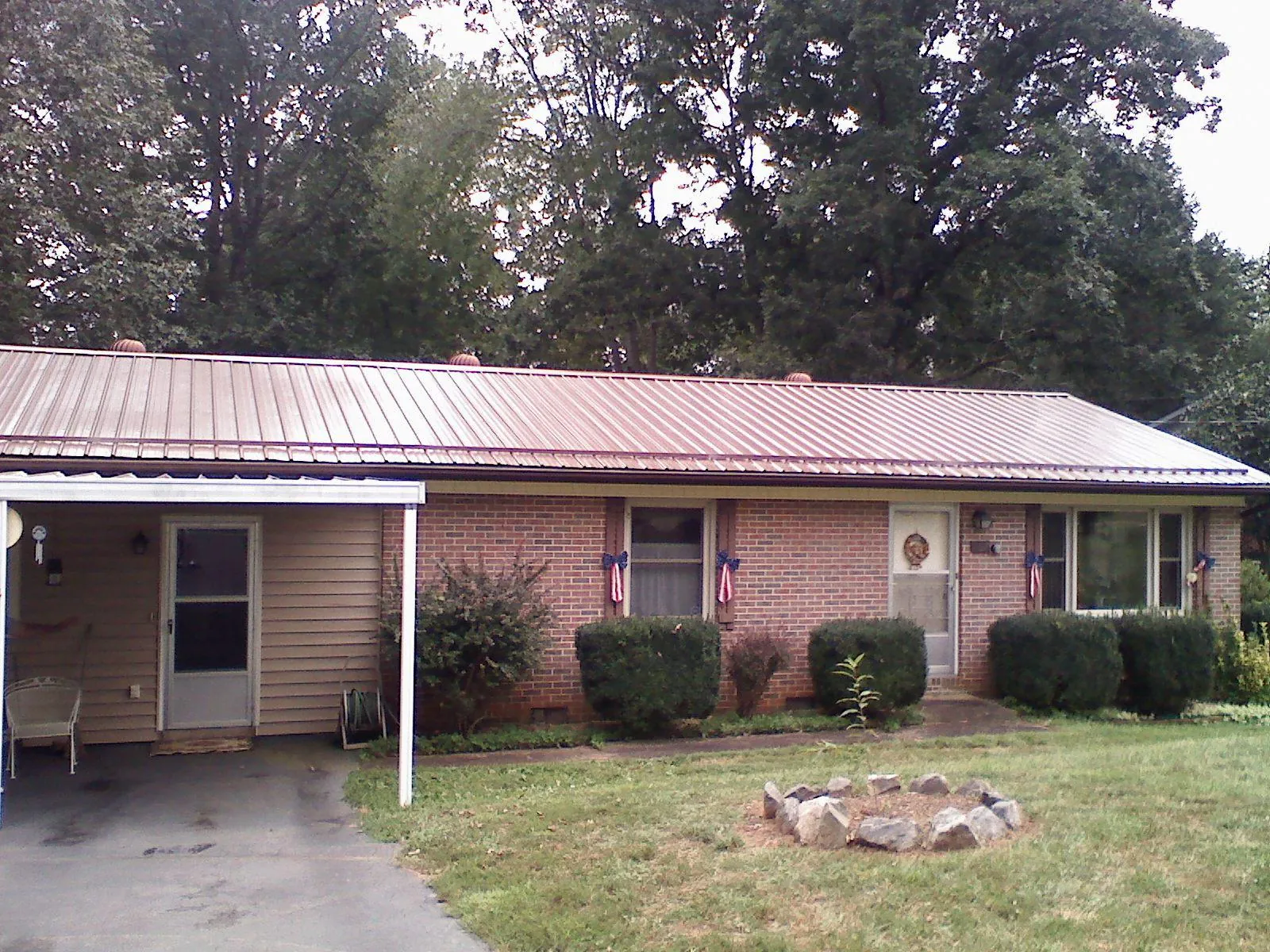 Bronze metal roof and carport on a brick ranch home — Roof Repair work by our crew in Borup