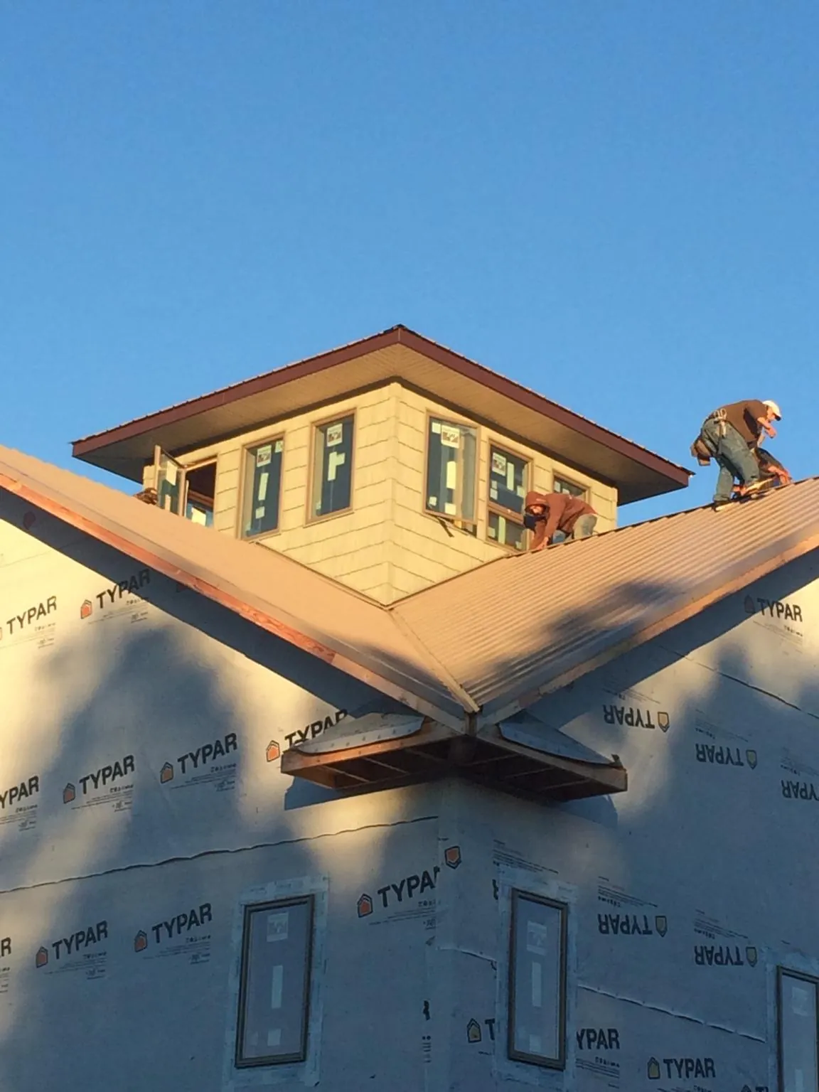 Roofers working around a rooftop cupola on a new metal roof at sunset — Roof Waterproofing in Borup by Roofing Brothers
